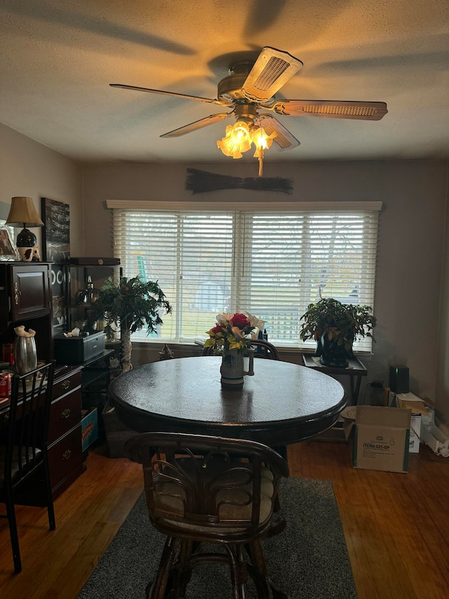 dining room featuring dark wood-type flooring, a textured ceiling, and ceiling fan