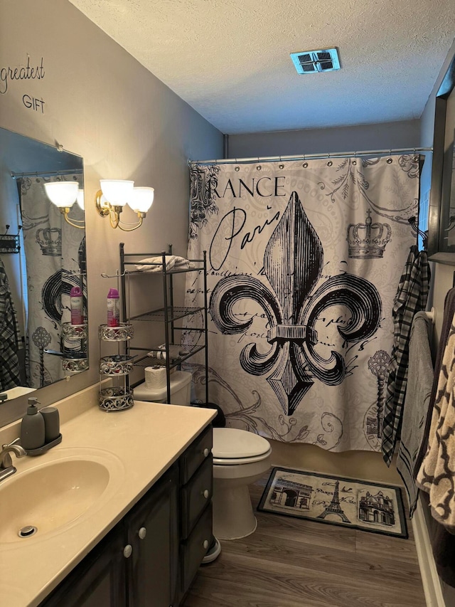 bathroom with vanity, toilet, hardwood / wood-style flooring, and a textured ceiling