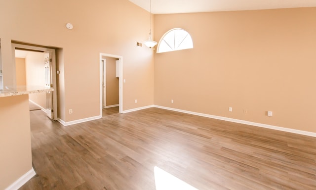 empty room featuring high vaulted ceiling and hardwood / wood-style flooring