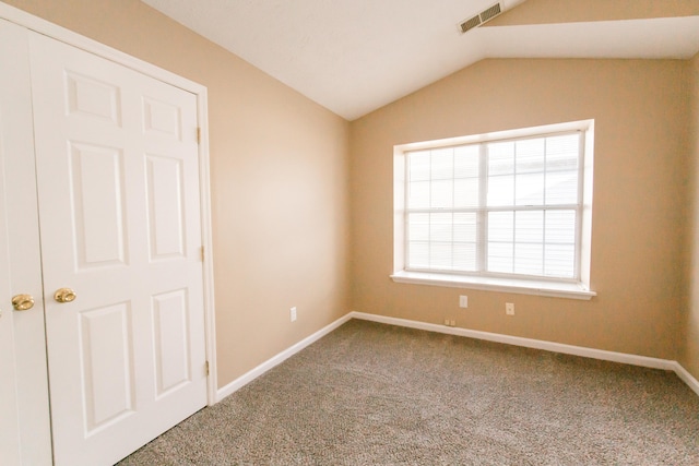 empty room with carpet flooring and lofted ceiling