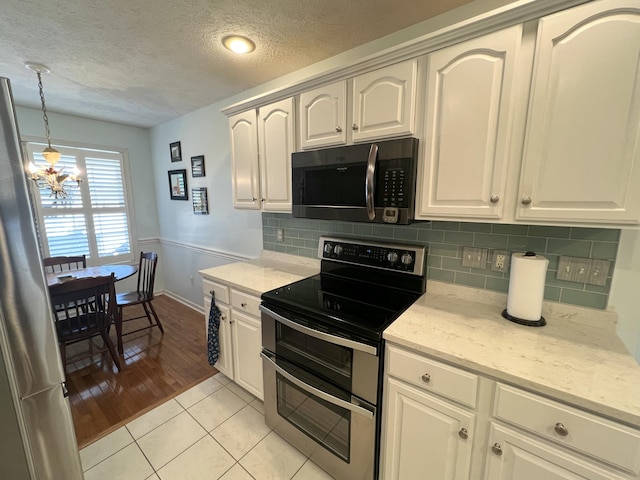 kitchen with light hardwood / wood-style flooring, pendant lighting, an inviting chandelier, white cabinetry, and appliances with stainless steel finishes