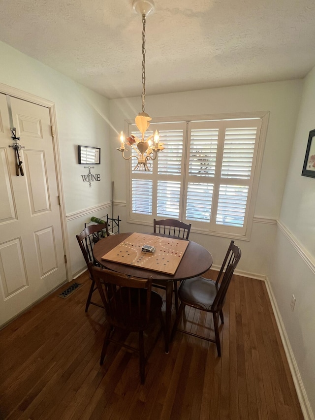 dining room featuring dark wood-type flooring, a notable chandelier, and a textured ceiling