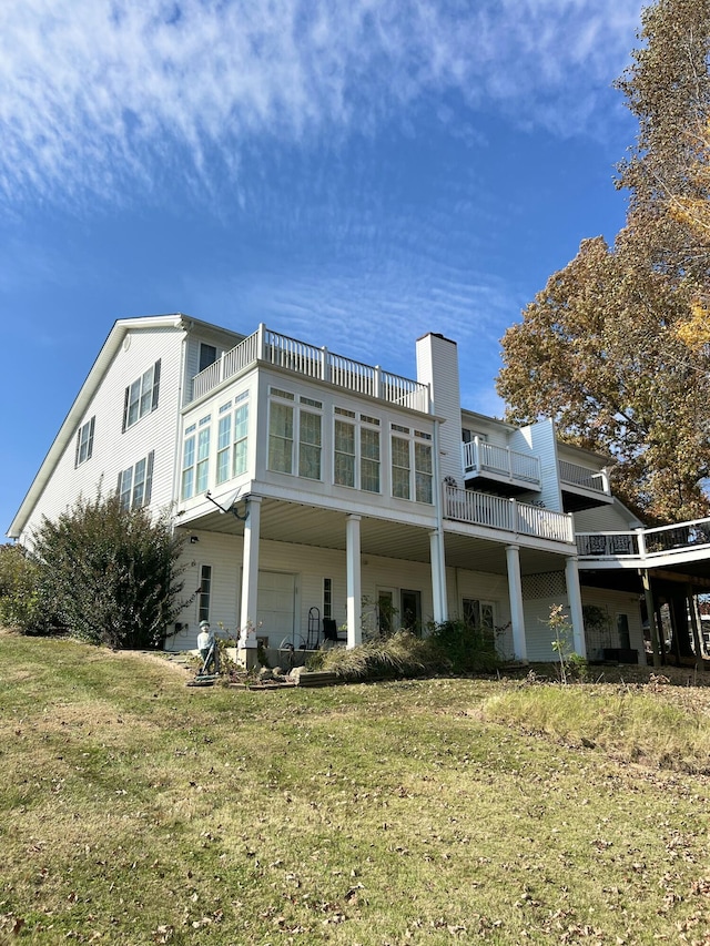 rear view of property with a yard and a balcony