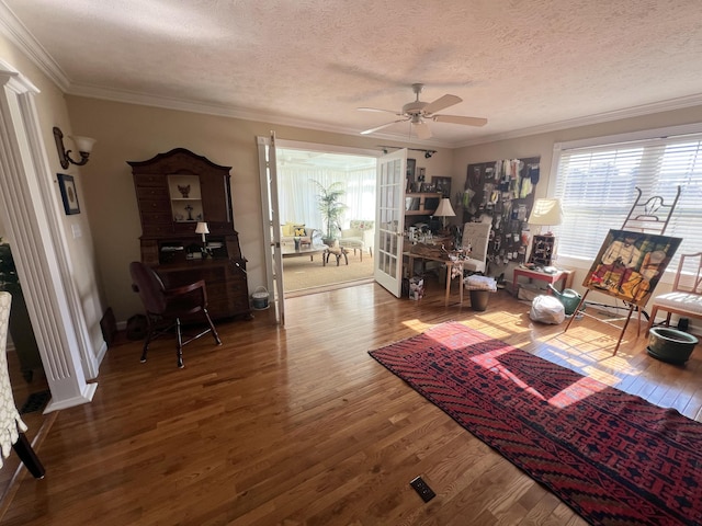 living area with crown molding, a textured ceiling, hardwood / wood-style flooring, and ceiling fan