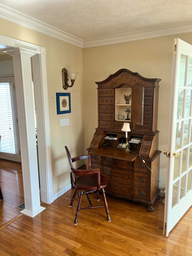 home office with ornamental molding, a textured ceiling, and light wood-type flooring