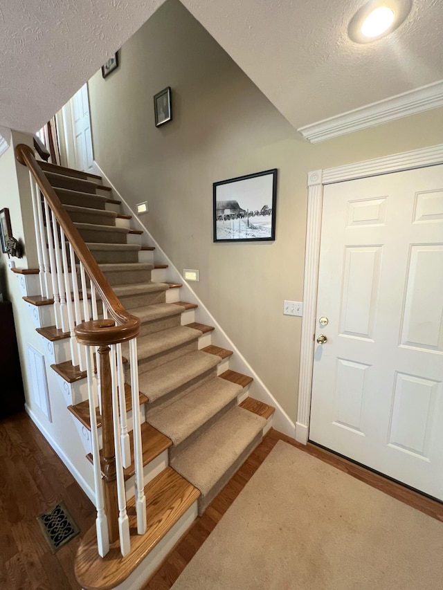 stairway featuring hardwood / wood-style flooring and a textured ceiling