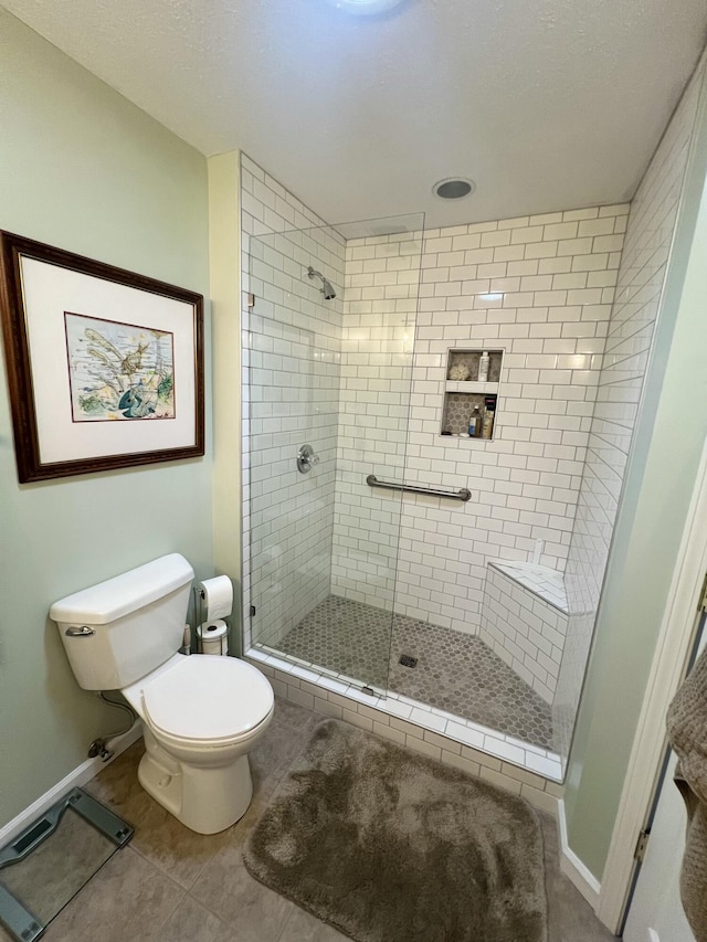 bathroom featuring toilet, tile patterned floors, and a shower with shower door