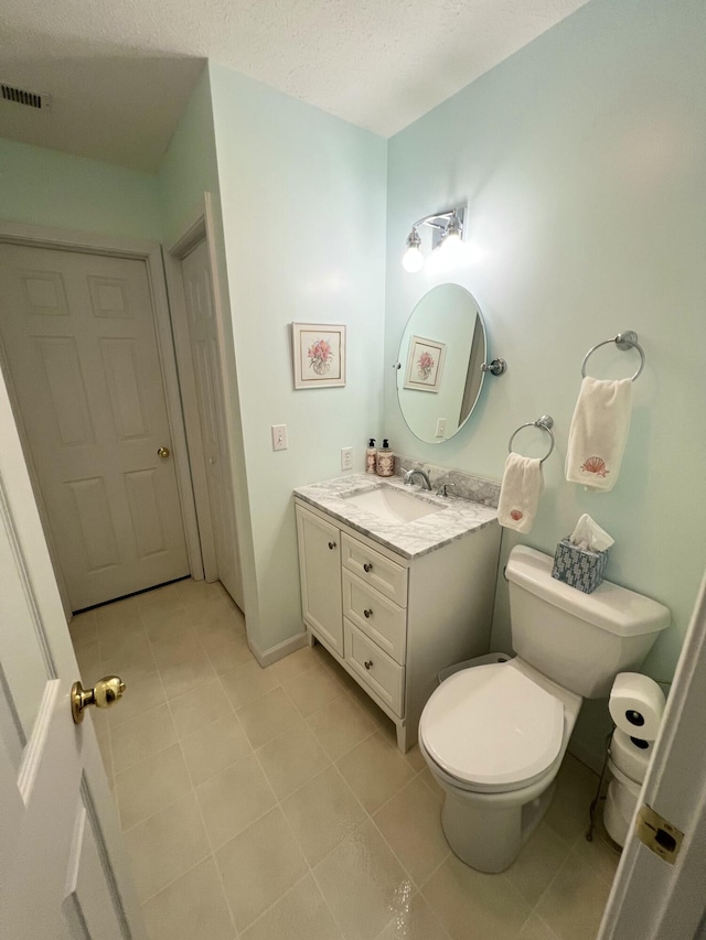 bathroom with vanity, a textured ceiling, toilet, and tile patterned floors