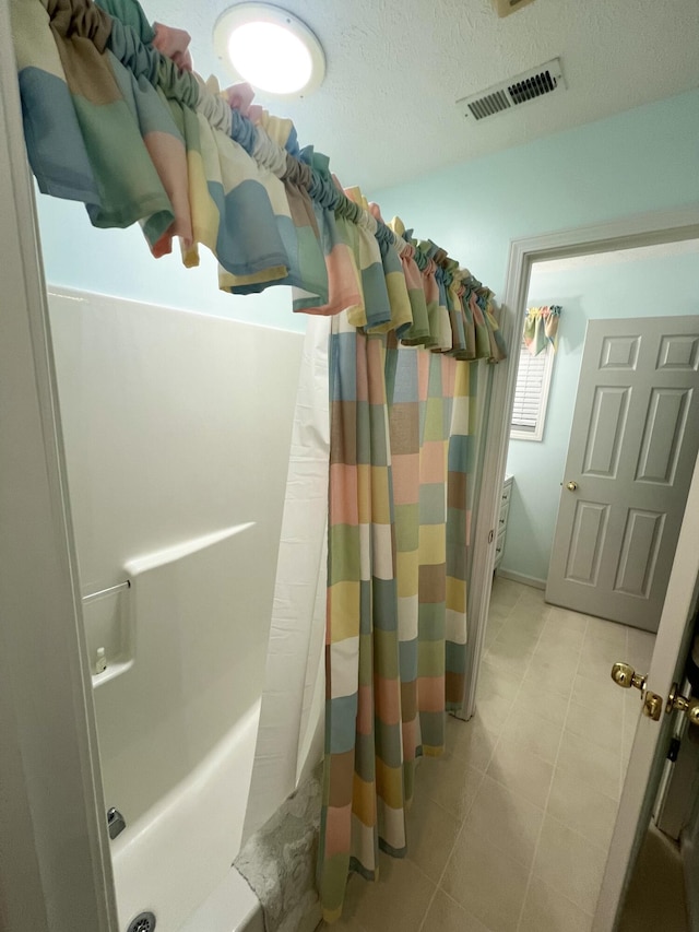 bathroom with a shower with shower curtain and a textured ceiling