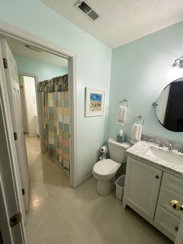 bathroom with tile patterned floors, toilet, vanity, a textured ceiling, and walk in shower