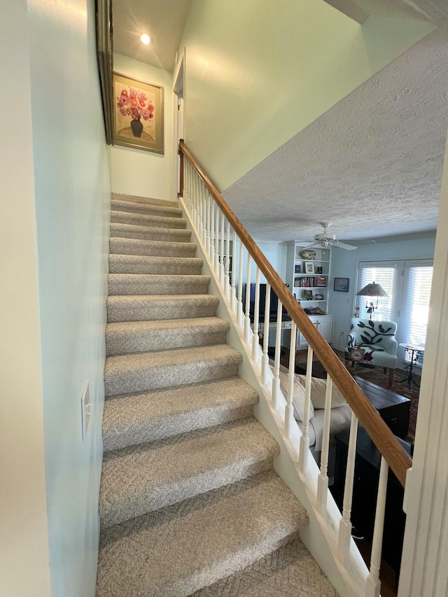 staircase featuring a textured ceiling and ceiling fan