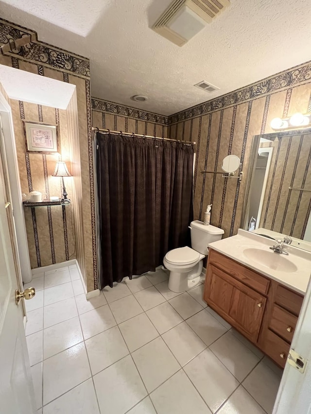 bathroom with vanity, toilet, tile patterned floors, and a textured ceiling