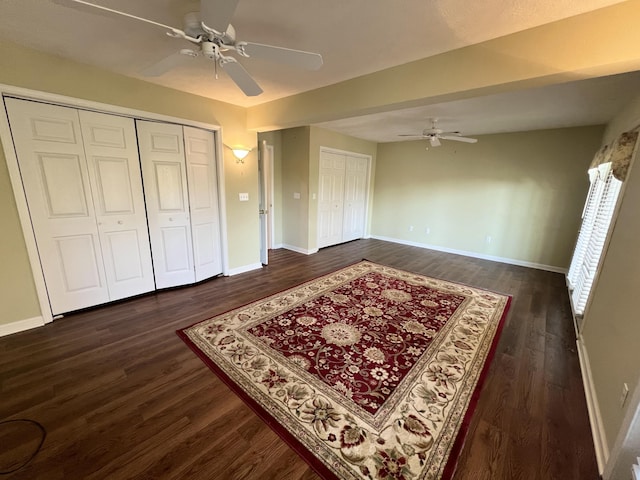 bedroom featuring ceiling fan, two closets, and dark hardwood / wood-style flooring