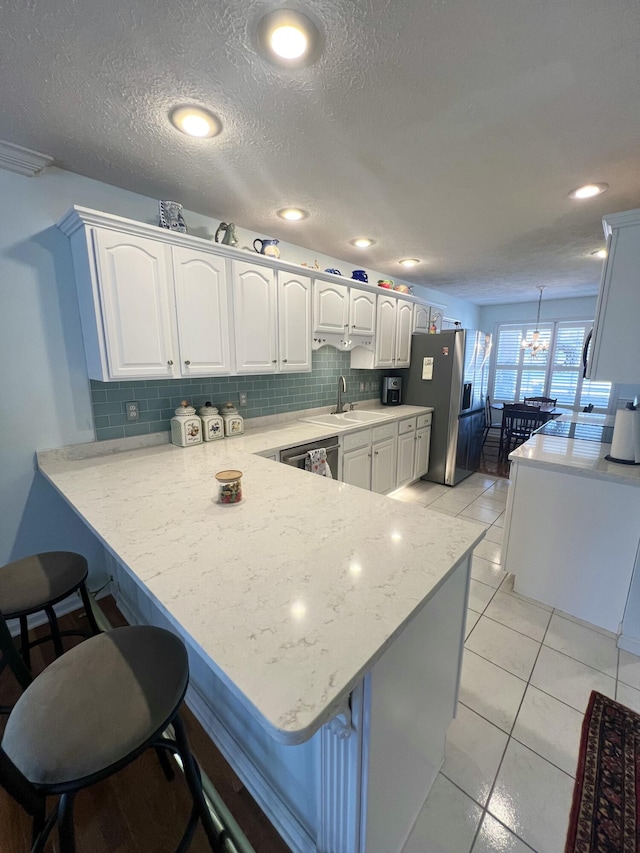 kitchen with kitchen peninsula, white cabinetry, and a kitchen bar