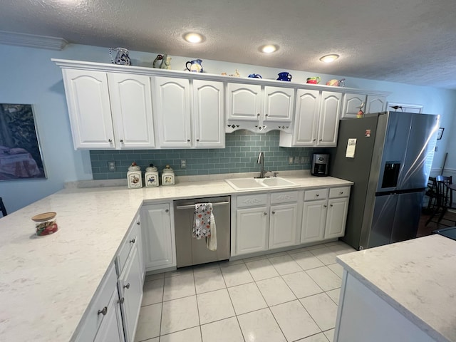 kitchen with tasteful backsplash, appliances with stainless steel finishes, sink, white cabinetry, and light tile patterned floors