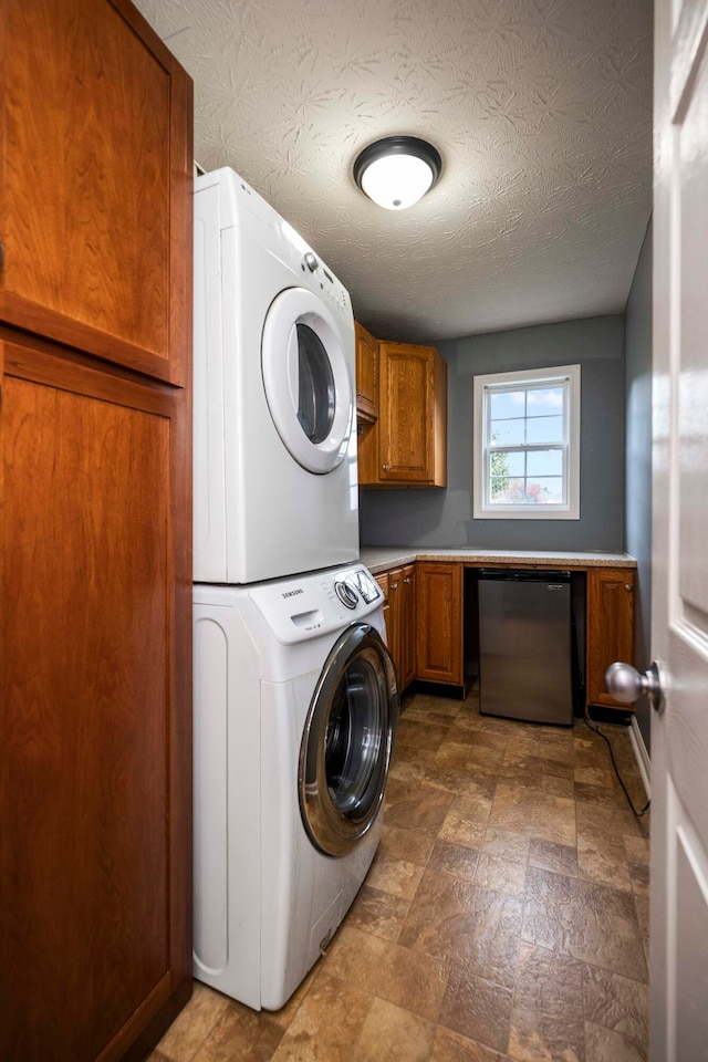 laundry room featuring a textured ceiling, cabinets, and stacked washer and dryer