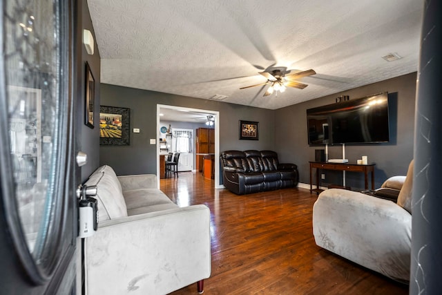 living room featuring a textured ceiling, ceiling fan, and dark hardwood / wood-style flooring