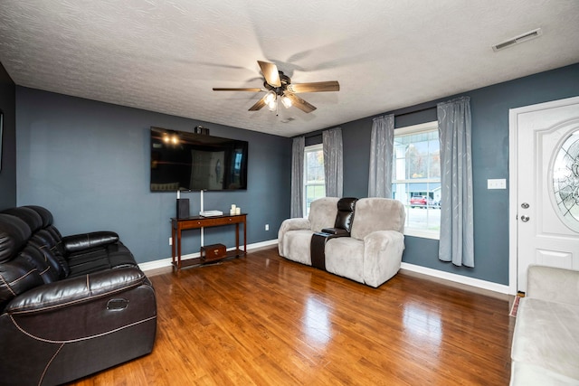 living room with hardwood / wood-style floors, a textured ceiling, and ceiling fan