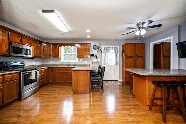 kitchen with sink, a kitchen bar, a textured ceiling, a center island, and stainless steel appliances