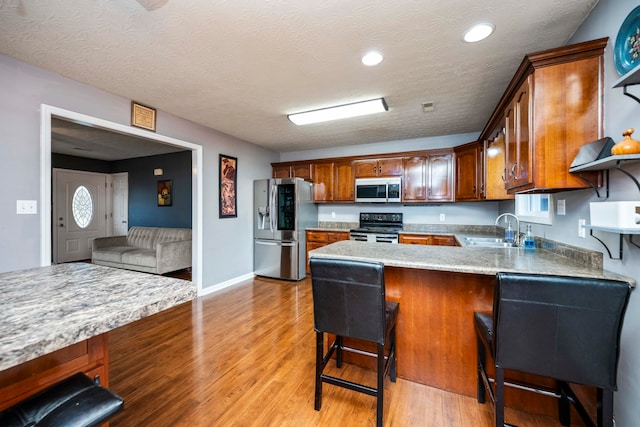 kitchen with sink, a kitchen breakfast bar, kitchen peninsula, and stainless steel appliances