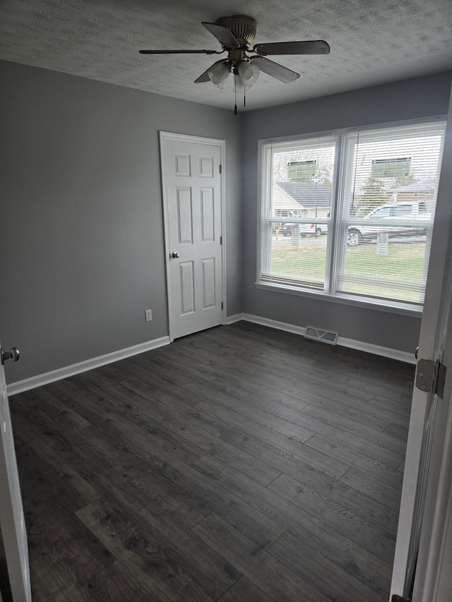 spare room featuring dark wood-type flooring, ceiling fan, and a textured ceiling