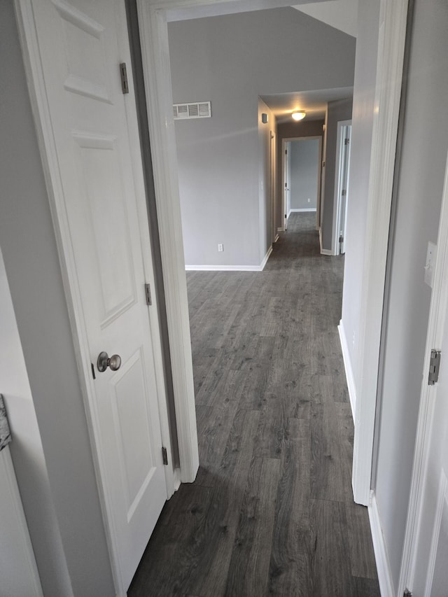 hallway with dark hardwood / wood-style flooring and lofted ceiling