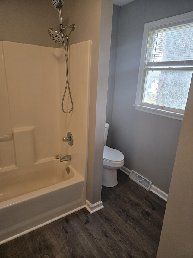 bathroom with hardwood / wood-style floors, toilet, and bathing tub / shower combination