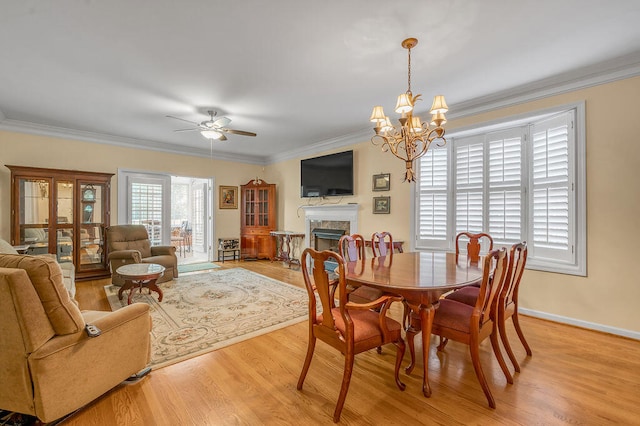 dining area with ceiling fan with notable chandelier, light wood-type flooring, and crown molding