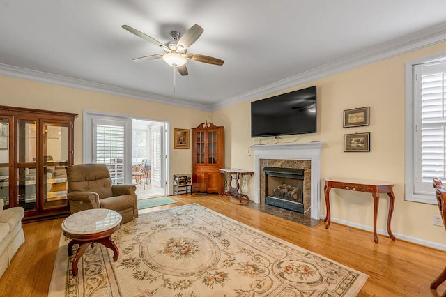 living room featuring ornamental molding, a fireplace, light hardwood / wood-style floors, and ceiling fan