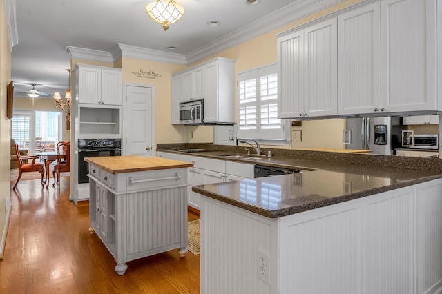 kitchen with butcher block counters, black oven, white cabinetry, and a kitchen island