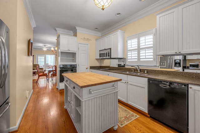 kitchen with white cabinets, black appliances, and butcher block counters