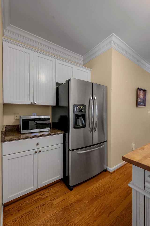 kitchen with white cabinets, stainless steel appliances, light hardwood / wood-style floors, and crown molding