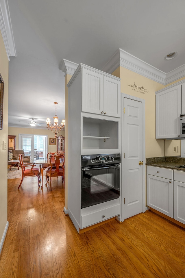 kitchen with white cabinets, oven, and crown molding