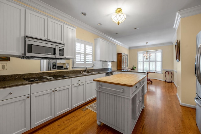 kitchen with black appliances, butcher block countertops, white cabinetry, and ornamental molding