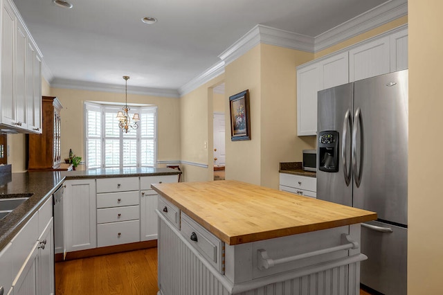 kitchen with wooden counters, appliances with stainless steel finishes, white cabinets, and a kitchen island