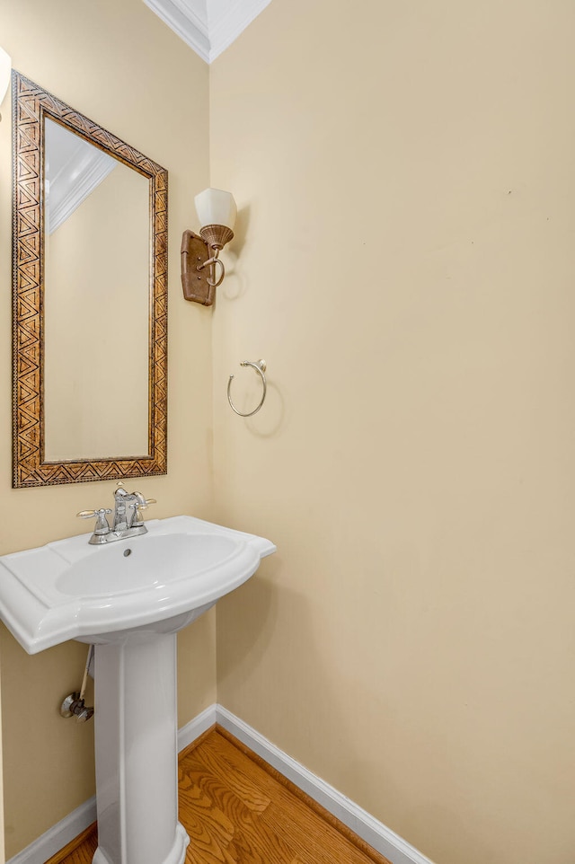 bathroom featuring sink, hardwood / wood-style floors, and ornamental molding