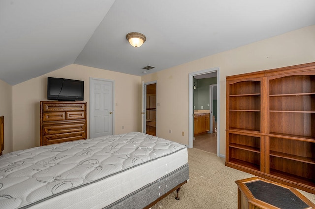 carpeted bedroom with connected bathroom and vaulted ceiling