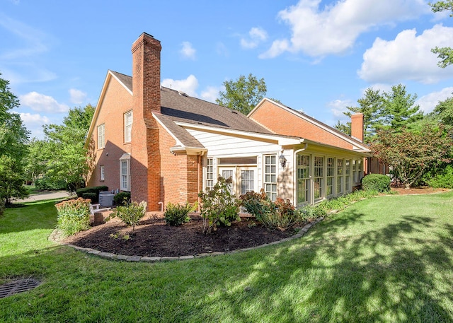 view of side of property with a lawn and central AC