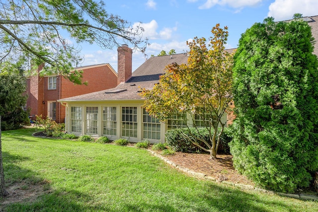 rear view of property with a lawn and a sunroom