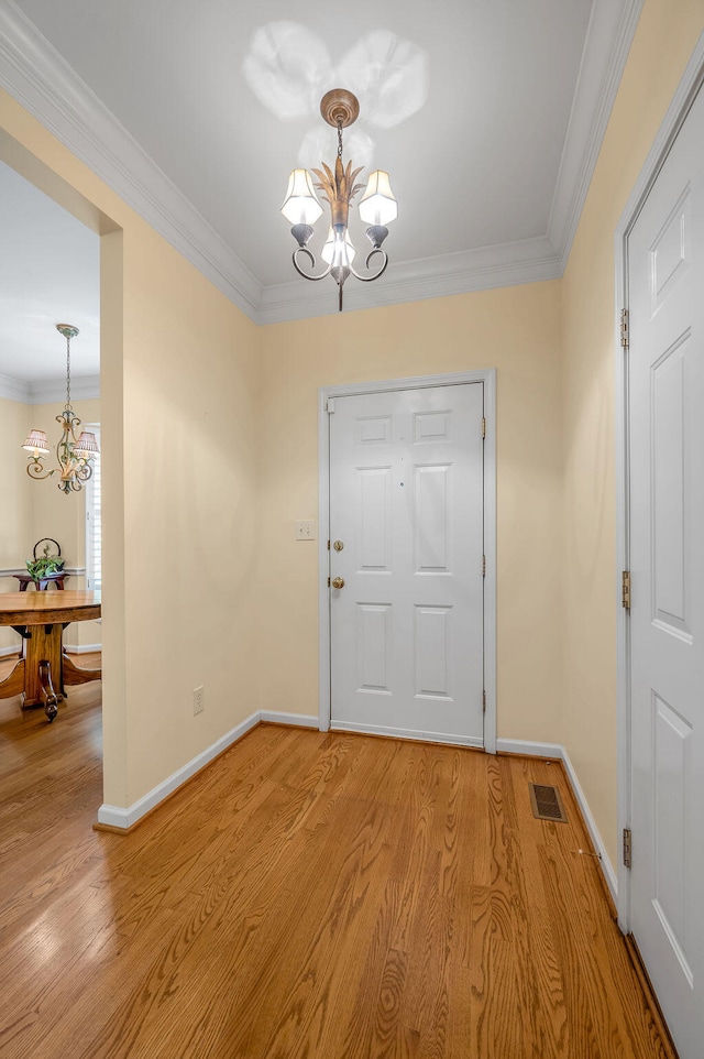 entrance foyer with light wood-type flooring, a chandelier, and crown molding