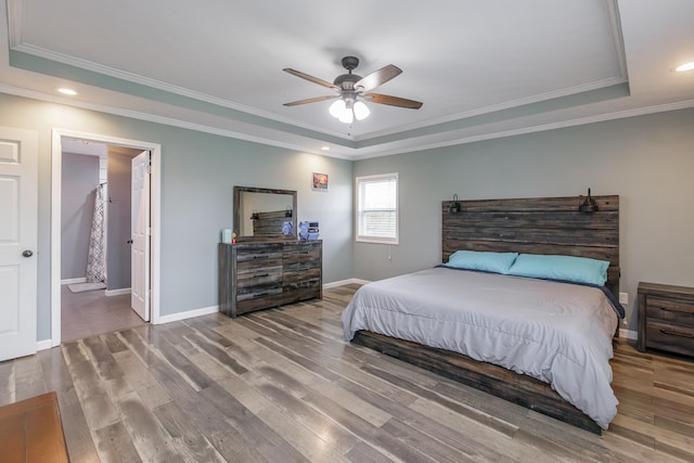 bedroom with hardwood / wood-style floors, ensuite bath, ceiling fan, and a tray ceiling