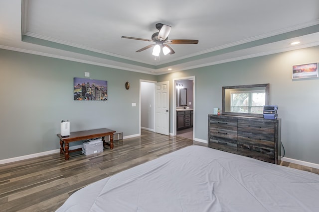 bedroom featuring ensuite bath, dark wood-type flooring, ceiling fan, crown molding, and a tray ceiling