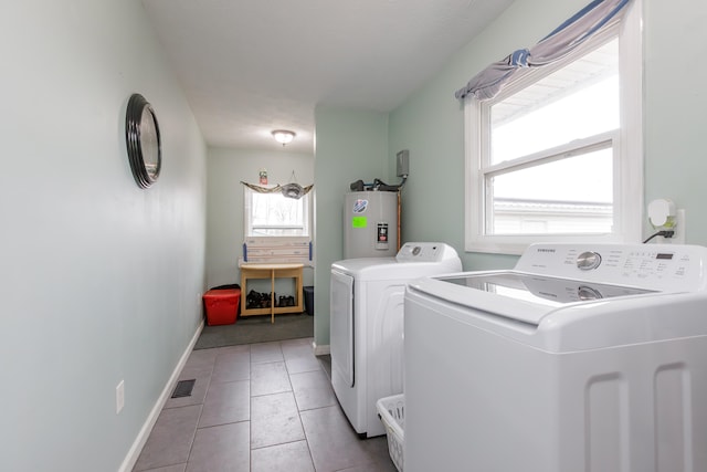 laundry area with electric water heater, plenty of natural light, light tile patterned floors, and washing machine and clothes dryer