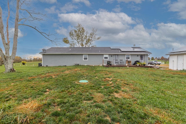 rear view of house featuring a deck, solar panels, and a yard