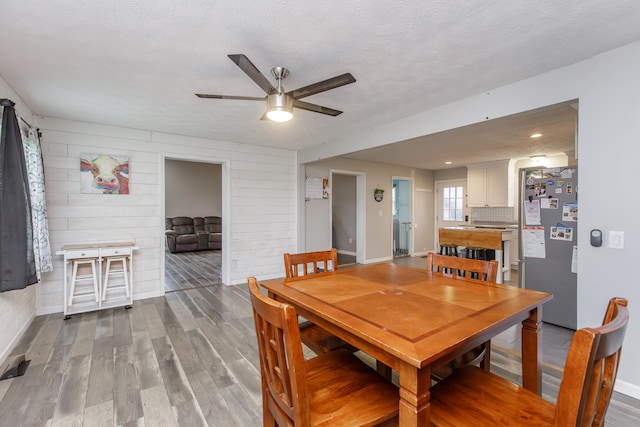 dining room with hardwood / wood-style flooring, ceiling fan, and a textured ceiling