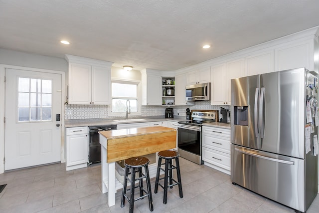 kitchen with a center island, white cabinets, sink, a kitchen breakfast bar, and appliances with stainless steel finishes