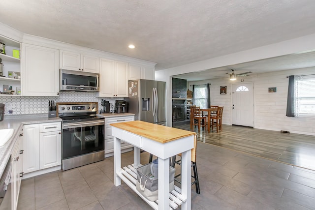 kitchen with appliances with stainless steel finishes, a textured ceiling, ceiling fan, and white cabinets