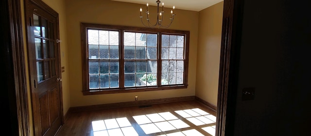 spare room with a chandelier and hardwood / wood-style flooring