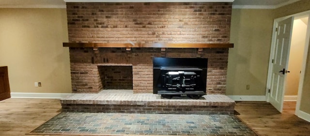 interior details with a brick fireplace, wood-type flooring, and crown molding