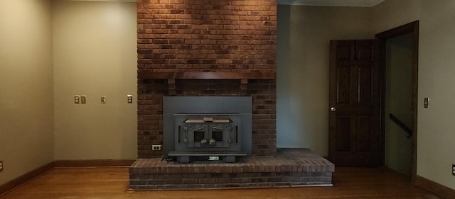 unfurnished living room featuring a wood stove, ornamental molding, and hardwood / wood-style flooring